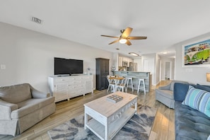 A modern living room with a flat-screen TV, a coffee table, a sofa, and a dining area with chairs. - Lakefront 226 has all the updates, all the convenience, and just needs you! (Miramar Beach)