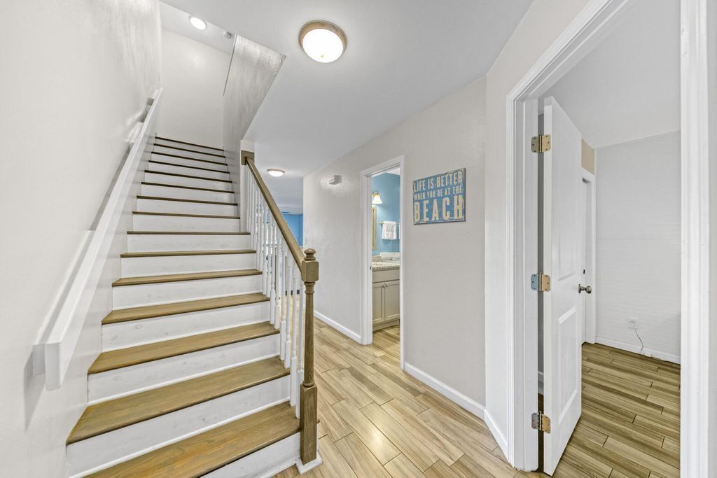 A staircase with wooden steps and white railings leading to a kitchen area.