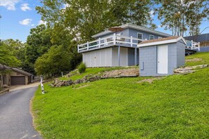 Et tosset hus med balkon, et lille skur og en indkørsel.