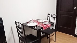 A dining area with a table set for four, black chairs, and a red and white tablecloth. - Relaxing 1-Bedroom Condo Unit (by Lee Portum) (Marilao)