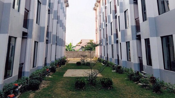 A modern building with a symmetrical facade, multiple windows, and a central pathway leading to a small garden area. - Relaxing 1-Bedroom Condo Unit (by Lee Portum) (Marilao)