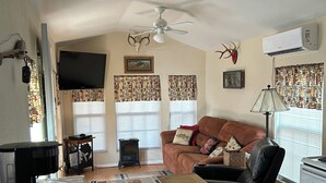 Ein gemütliches Wohnzimmer mit einem Holzesstisch, einer Couch, einem Couchtisch, einem Kamin und einem Deckenventilator.