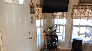 Ein Wohnzimmer mit Flachbildfernseher, Kamin, Teppich und einer Tür mit Fenster.