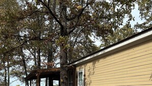 Eine rustikale Holzhütte mit überdachter Veranda, einer Texas-Flagge und Blick auf einen See.