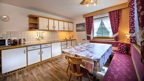 A compact kitchen with a dining area, wooden cabinets, a microwave, and a table set for two.