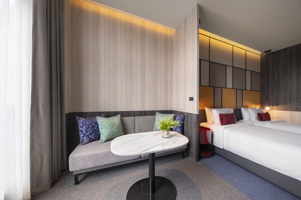 A modern hotel room with a sofa, a small round table, a bed, and a nightstand. - Ramada Plaza by Wyndham Bangkok Sukhumvit 48 (Bangkok)