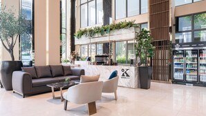 A modern lobby with a marble reception desk, seating area, and a view of the city. - Ramada Plaza by Wyndham Bangkok Sukhumvit 48 (Bangkok)