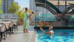 A rooftop pool area with a glass enclosure, outdoor seating, and a view of high-rise buildings. - Ramada Plaza by Wyndham Bangkok Sukhumvit 48 (Bangkok)