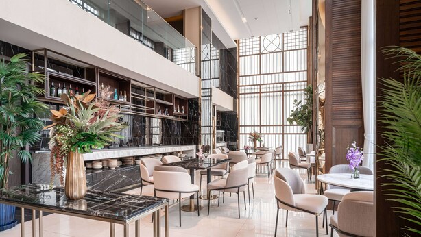 A modern hotel lobby with a spacious seating area, marble flooring, and a bar with shelves of bottles. - Ramada Plaza by Wyndham Bangkok Sukhumvit 48 (Bangkok)
