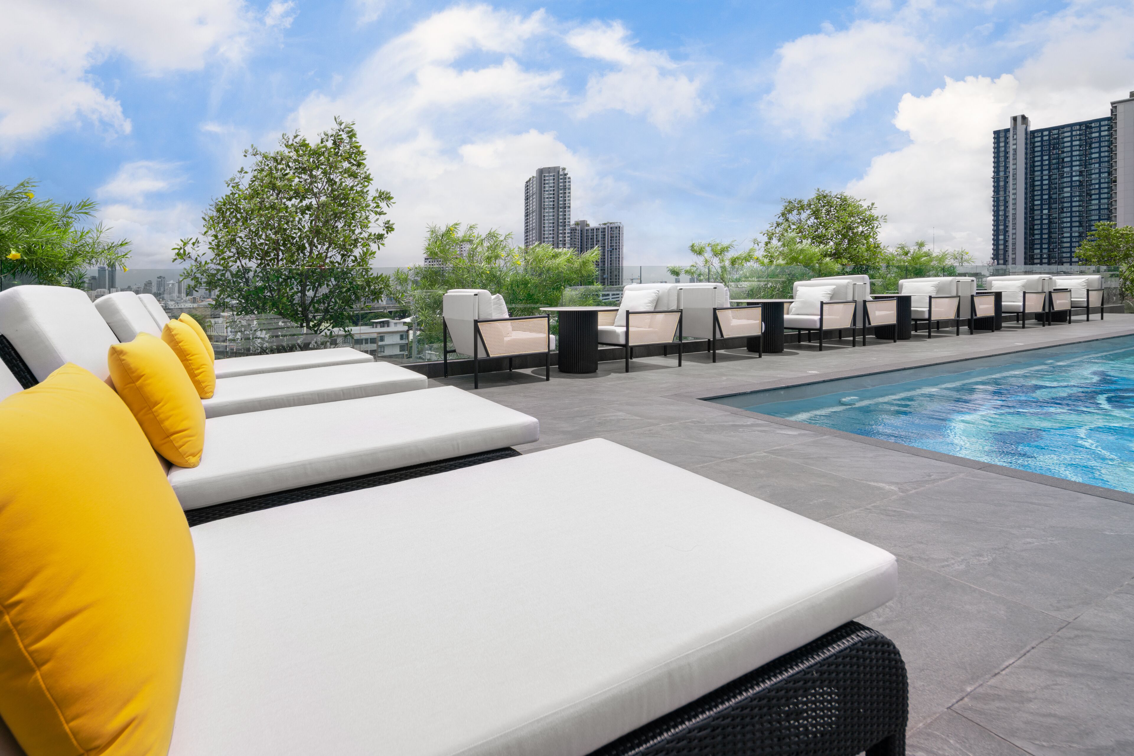 A rooftop pool area with lounge chairs and a view of the city skyline.
