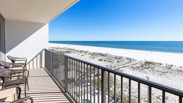 Un balcon avec vue sur la plage, comprenant une piscine et du mobilier d’extérieur.