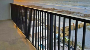 Un balcon avec vue sur la plage et l’océan au coucher du soleil.