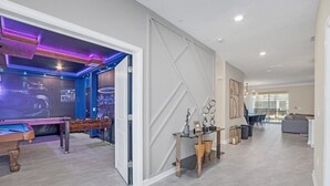 Ett modernt vardagsrum med ett fotbollsspel, ett soffbord i glas och en soffa.