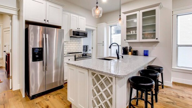 A modern kitchen with white cabinetry, stainless steel appliances, a granite countertop, and bar stools. - Excellent 3BR/2BA PRIME Location! (Louisville)
