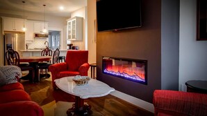 A modern living room with a fireplace, red furniture, and a kitchen in the background. - Excellent 3BR/2BA PRIME Location! (Louisville)
