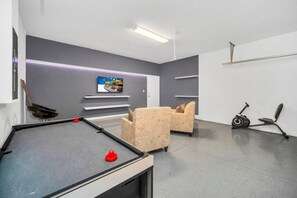 Una habitación moderna con mesa de billar, sofá y televisión.