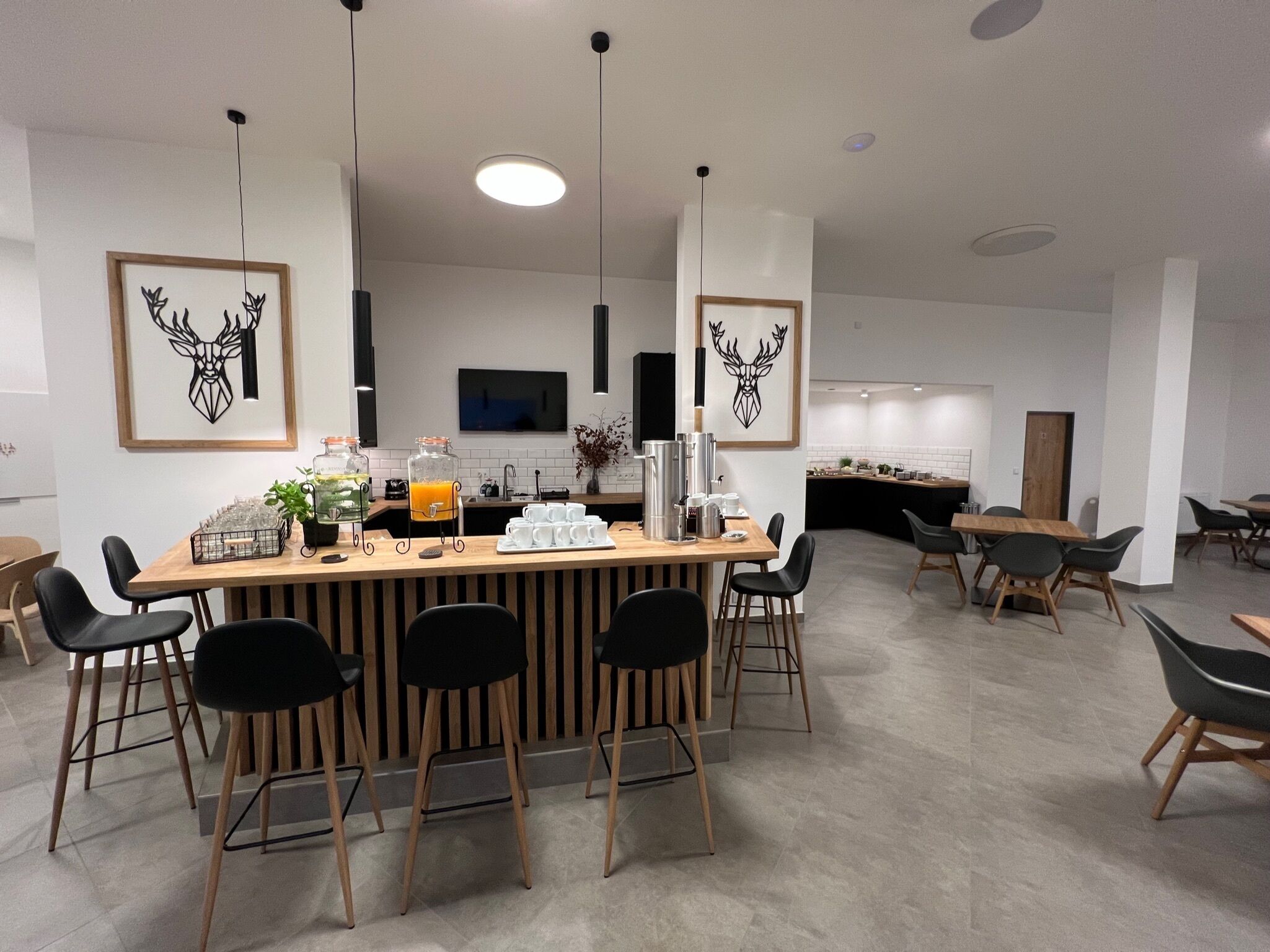 Un comedor moderno con barra central, sillas negras y un bufé con recipientes de vidrio.