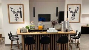 Una cocina moderna con una isla central, taburetes de bar, una estación de café y obras de arte enmarcadas en las paredes.