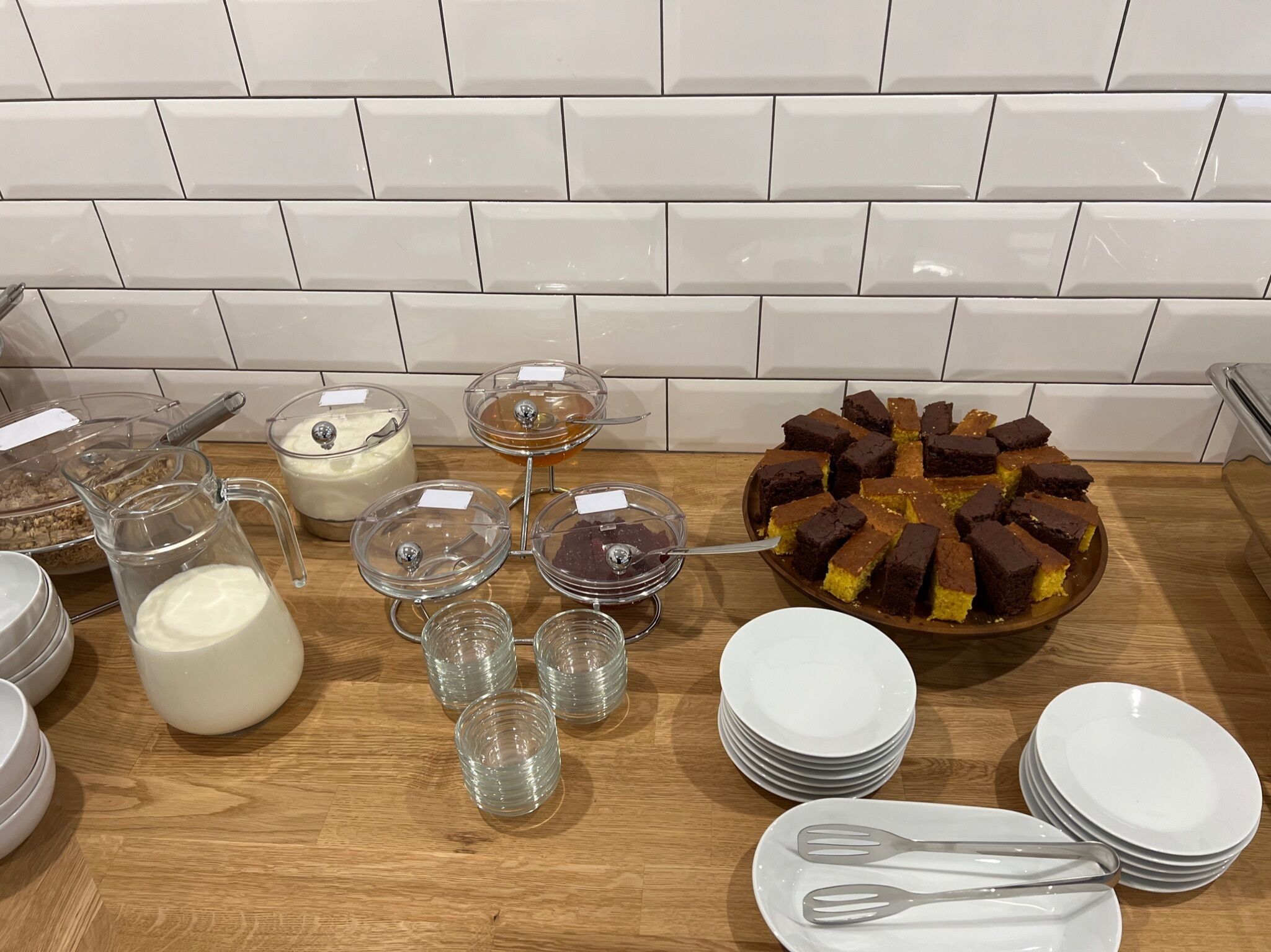 Mesa de buffet com diversos alimentos, incluindo um bolo, tigelas de sopa e um jarro de leite.