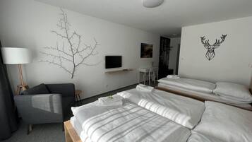 A hotel room with a large bed, a sofa, a desk, and a TV.
