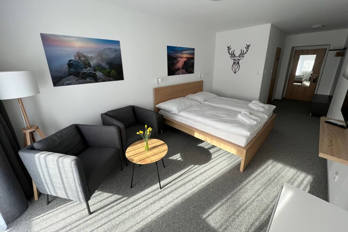 Ein modernes Hotelzimmer mit einem großen Bett, einem Schreibtisch, einem Stuhl und zwei Bildern an der Wand.