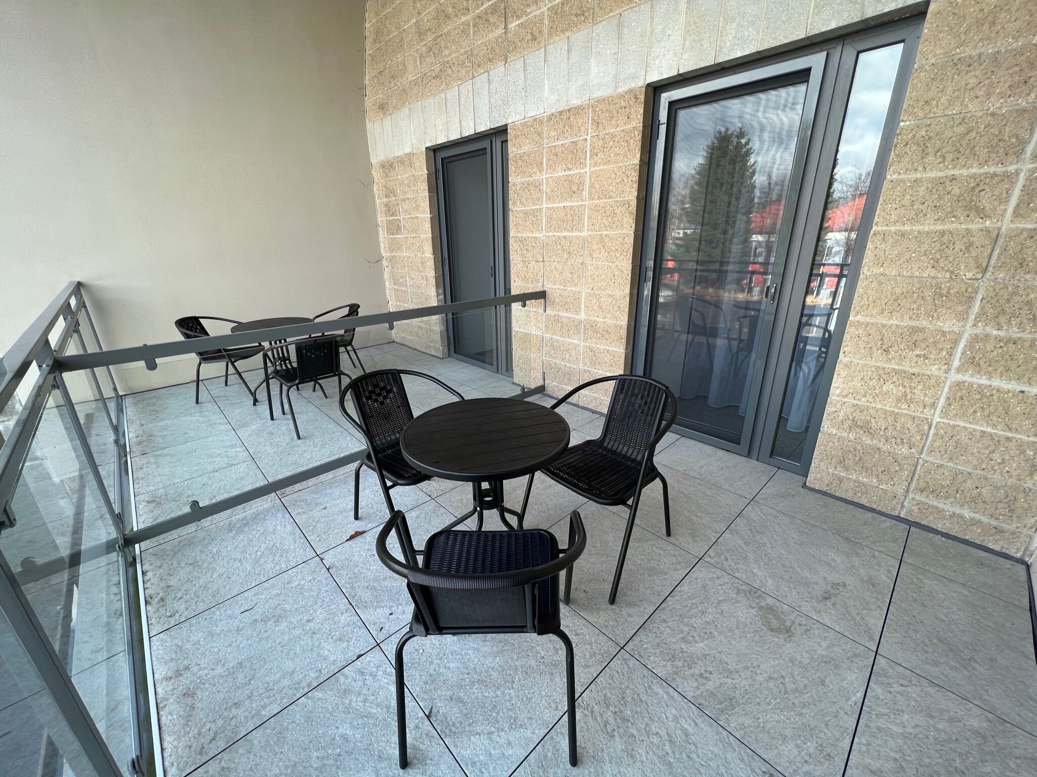 A balcony with a glass railing, a round table, and four chairs.