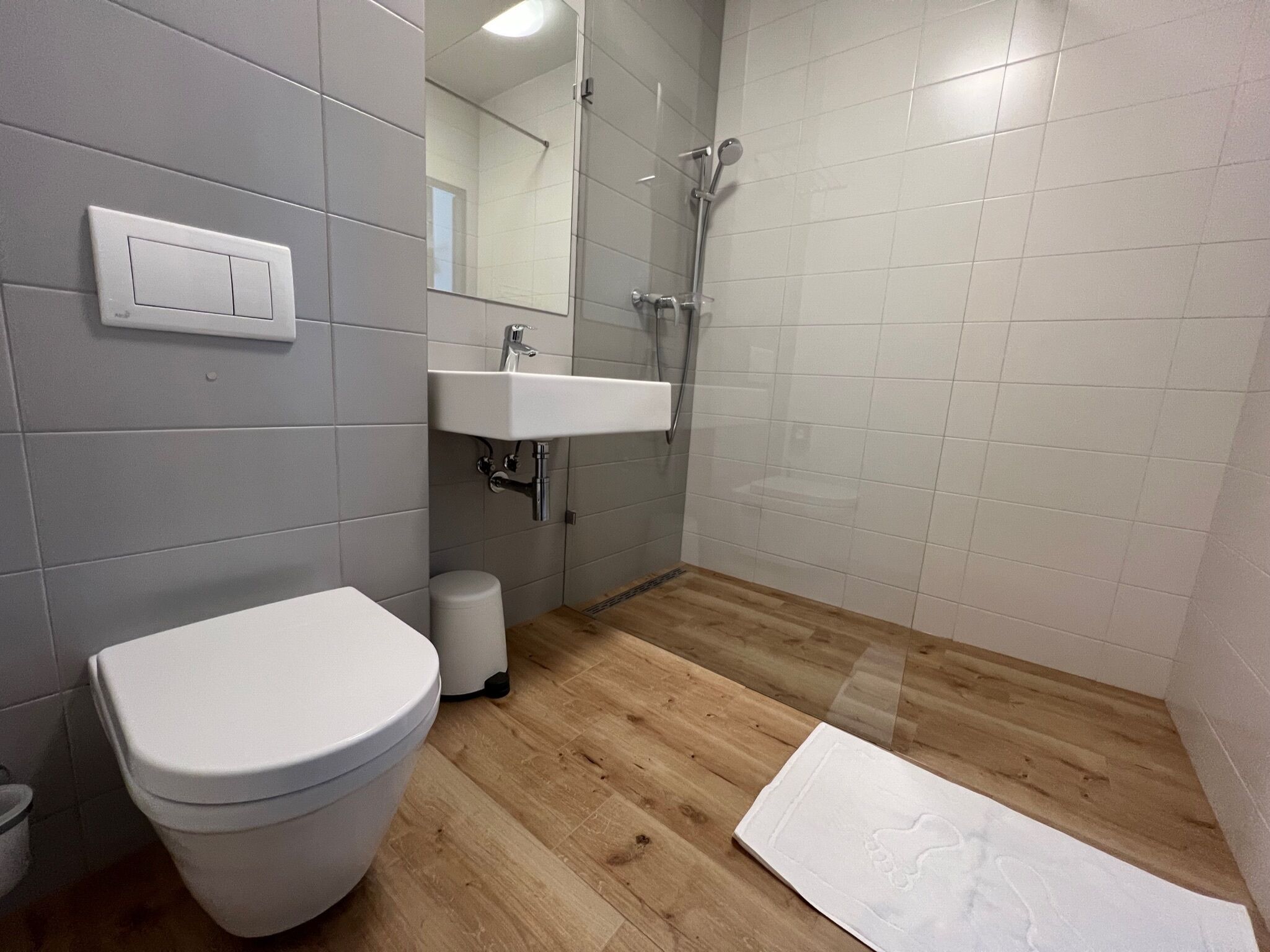 A modern bathroom with a toilet, sink, and shower.