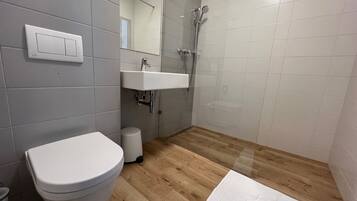 A modern bathroom with a toilet, sink, and shower.