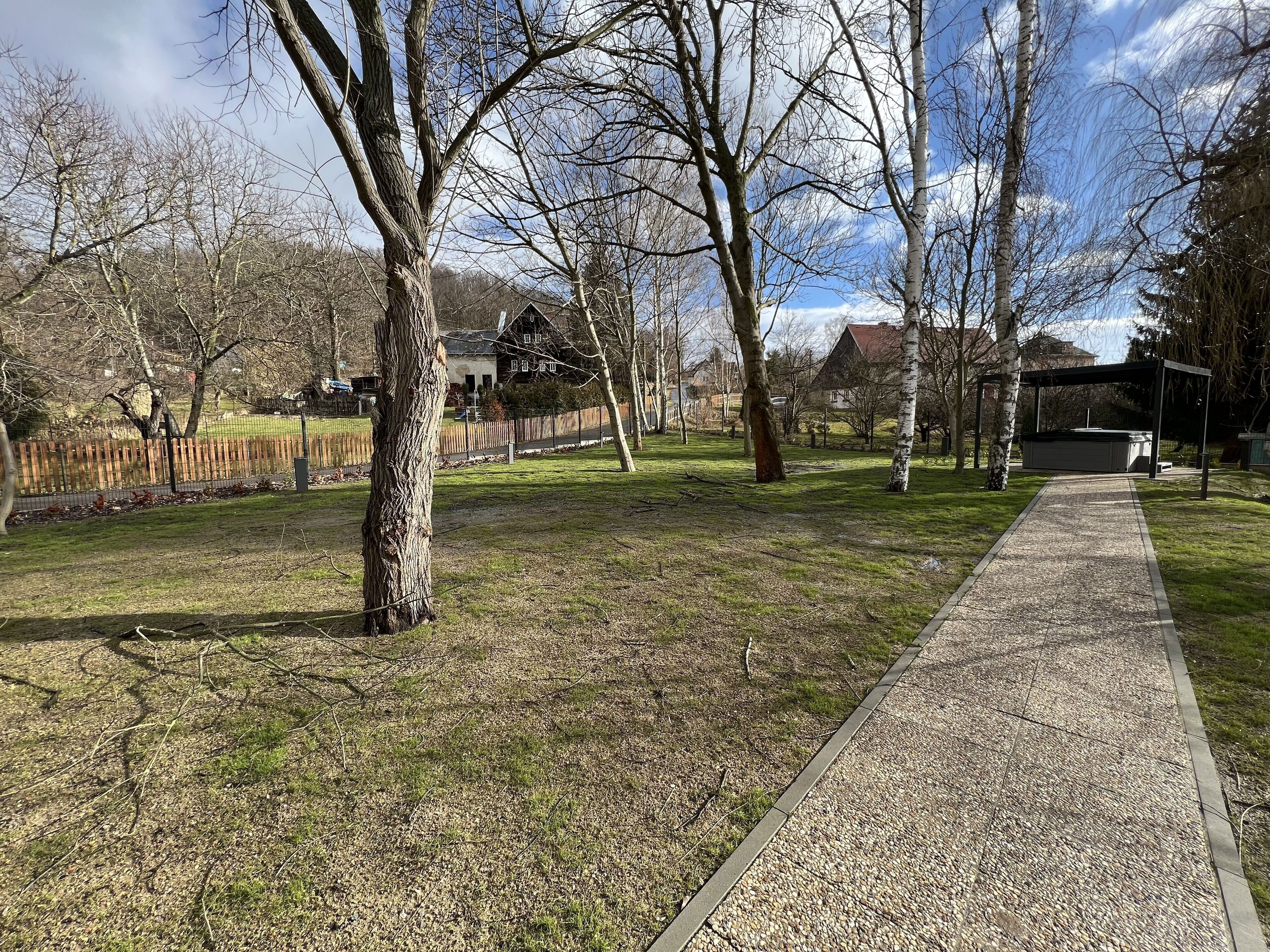 A park with a gravel path, trees, and a wooden fence.