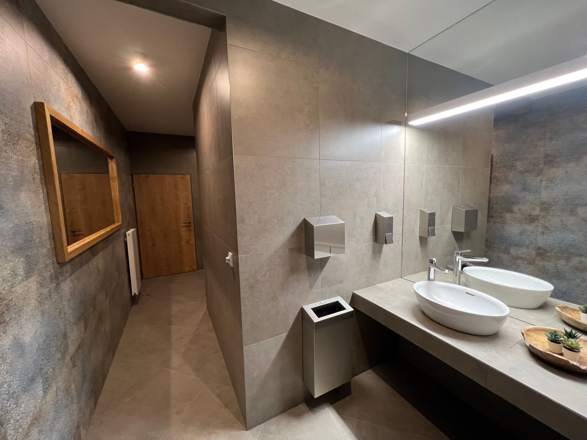 Un bagno moderno con due lavabi, uno specchio e un cestino.
