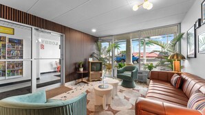 A lobby with a sofa, chairs, a TV, and a magazine rack. - The Retro Hotel (Branson)