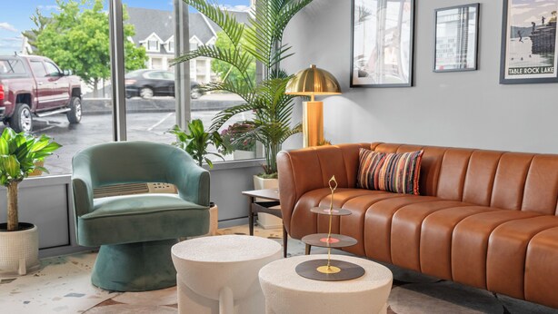 A modern living room with a leather sofa, a teal armchair, and a round coffee table. - The Retro Hotel (Branson)