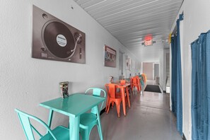 A corridor with teal and orange chairs, a wall-mounted record player, and an exit sign. - The Retro Hotel (Branson)