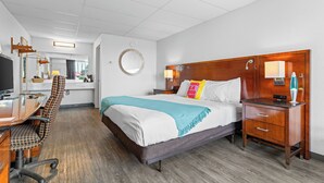 A hotel room with a bed, desk, chair, and a mirror. - The Retro Hotel (Branson)