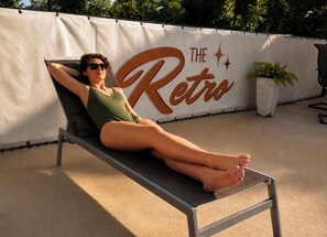 A person reclining on a lounge chair with a banner in the background reading 'THE Retro'. - The Retro Hotel (Branson)