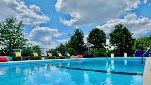 A swimming pool with clear blue water, surrounded by lounge chairs with yellow cushions. - The Retro Hotel (Branson)