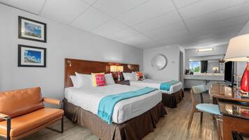A hotel room with two beds, a desk, a chair, and a bathroom visible through an open door.
