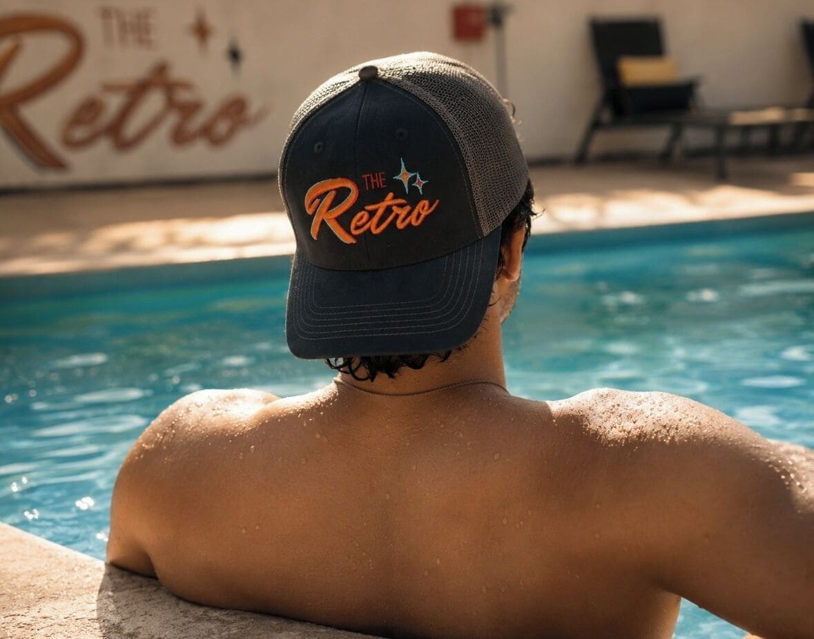 A person relaxing by a pool with a cap labeled 'The Retro.'