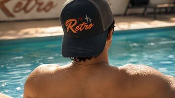 A person relaxing by a pool with a cap labeled 'The Retro.'