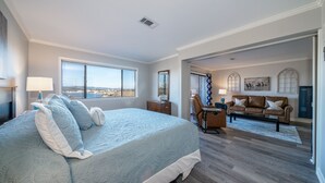 Un dormitorio con una cama grande, un escritorio, un sofá y vistas a la ciudad.