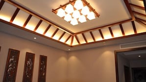 A room with a wooden ceiling design, recessed lighting, and three wall-mounted decorative panels. - Chunqiu Shuyuan Hotel (Feicheng)