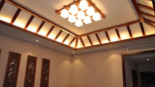 Une pièce dotée d’un plafond en bois décoratif, d’un éclairage encastré et de trois panneaux décoratifs fixés au mur.