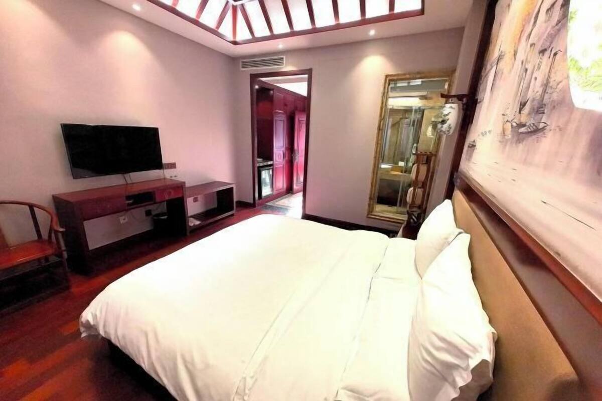 Una camera da letto con un letto grande, una TV a schermo piatto, un comò in legno e un quadro appeso al muro.
