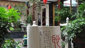 A traditional Chinese gate with calligraphy, surrounded by lush greenery and a red lantern. - Chunqiu Shuyuan Hotel (Feicheng)