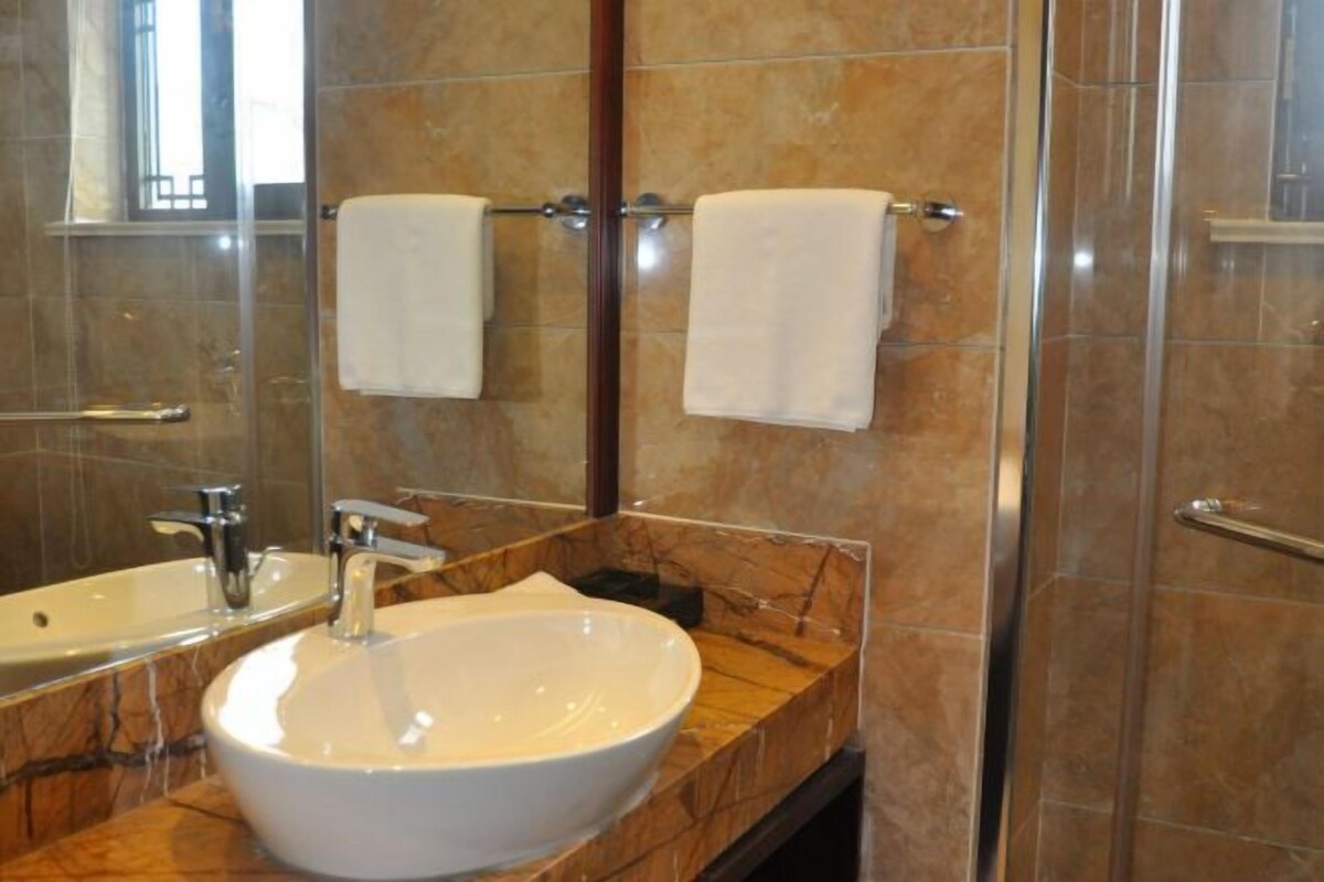 Un baño con lavamanos de mármol, un espejo y una cabina de ducha de cristal.