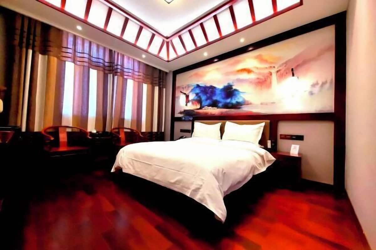Una camera d'albergo con un letto grande, un quadro appeso al muro e vista sulla città.
