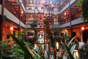 A multi-level atrium with a central staircase, surrounded by lush greenery and traditional decor. - Chunqiu Shuyuan Hotel (Feicheng)