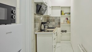A compact kitchen with a microwave, kettle, and a coffee maker on the counter.