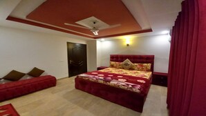 Quarto com cama vermelha, ventilador de teto e porta.