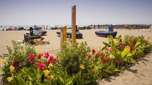 A beach with sun loungers, umbrellas, and a tall sign. - Sea Breeze Apartment | Spacious Terrace (Fuengirola)